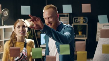 Kapalı kapılar ardında neşeli hipster çift gece ofisindeki cam levhalara bakıyor.