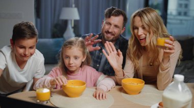 Gülümseyen aile sohbeti. Ebeveynler, kardeşler el sallıyor, dizüstü bilgisayar kamerası.