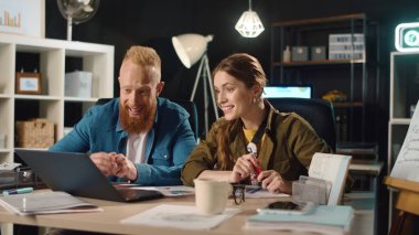 Genç işadamı ve iş kadını geceyi hipster ofisinde geçiriyorlar..