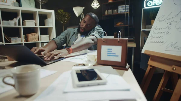 Porträt eines geschäftigen afrikanisch-amerikanischen Mannes, der in der Nähe seines Laptops im Büro telefoniert. — Stockfoto