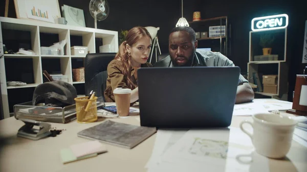 Afro man and hipster woman talking about solution on laptop screen in office.