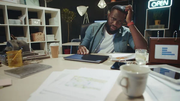 Portrait of stressed african american guy pondering in modern office.