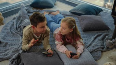 Evde akıllı telefon kullanan sevimli kardeşlerimiz var. Çocuklar beşlik çakıyor.