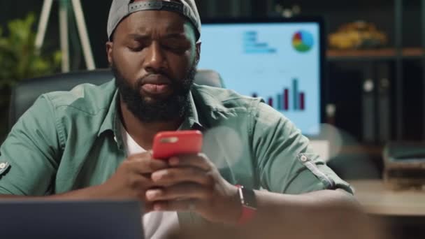 사무실에서 핸드폰으로 문자를 치고 있는 젊은 아프리카계 미국인을 감싼다. — 비디오