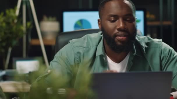 Porträt eines afrikanisch-amerikanischen Geschäftsmannes, der im Nachtbüro per Laptop spricht — Stockvideo