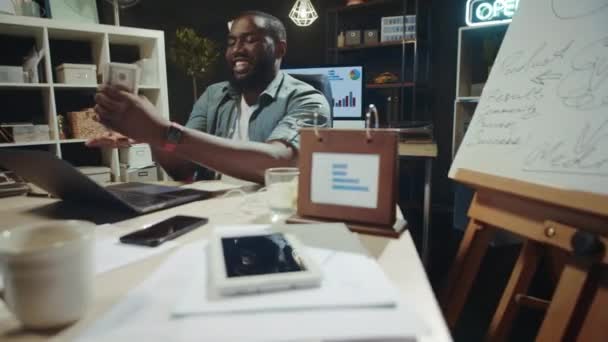 Cheerful african businessman stacking money at modern workplace in slow motion. — Stock Video