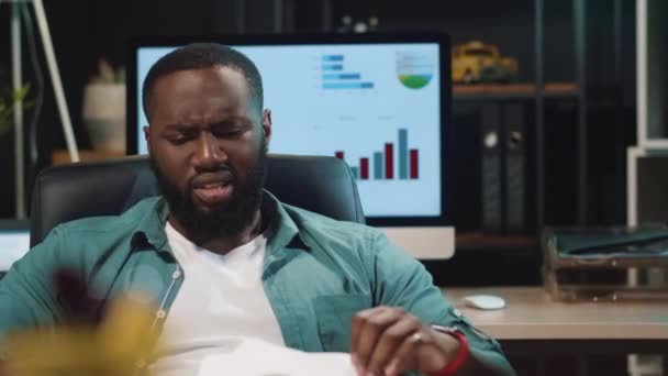 Nahaufnahme verärgert afrikanisch-amerikanischen Hipster Kerl suchen Diagramm im Nachtbüro — Stockvideo