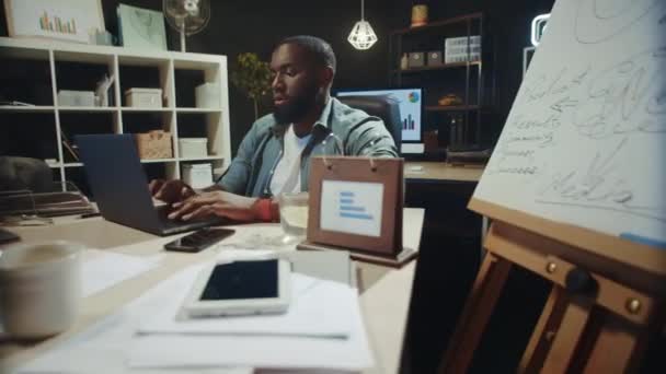 Hombre afroamericano sobrecargado de trabajo terminando proyecto en hipster coworking. — Vídeos de Stock