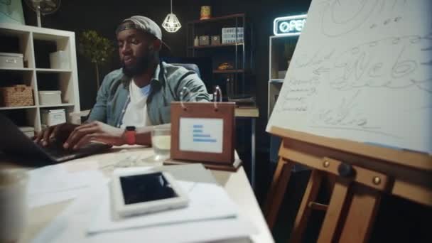 Gerente afro masculino sobrecarregado digitando no computador no escritório hipster. — Vídeo de Stock