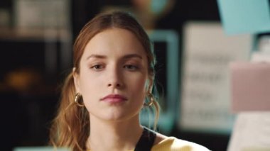 Hüsrana uğramış iş kadını, hipster ofisindeki cam panolardaki çıkartmalara bakıyor.