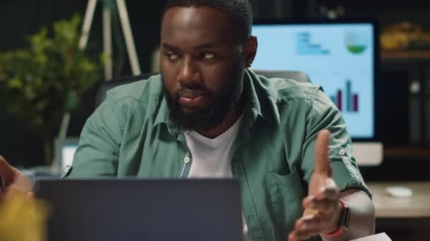 Κοντινό πλάνο απογοητευμένος afro επιχειρηματίας μιλάμε μέσω laptop στο γραφείο νύχτα — Αρχείο Βίντεο