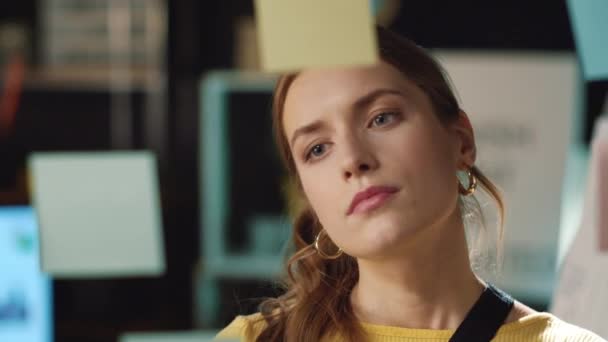 Closeup focused hipster girl reading stickers on glass board in hipster office — Stock Video