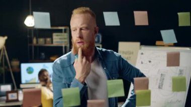Yakın plan düşünceli iş adamı birlikte çalışırken cam levhada etiketler görüyor..
