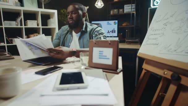 Focused african man reading documents in late office. Afro guy working overtime — Stock Video