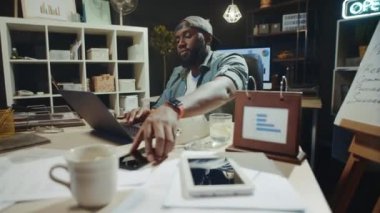 Meşgul Afro-Amerikan iş adamı hipster ofisinde cep telefonu arıyor..