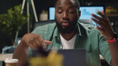 Odaklanmış afro iş adamı projeyi gece ofisinde görüntülü sohbet ile tartışıyor