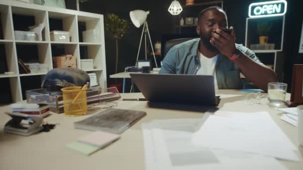 Jóképű afrikai üzletember beszél mobilon a hipszter irodában. — Stock videók