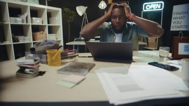 Frustrado afroamericano chico comprobar proyecto resultado en línea en la oficina oscura. — Vídeos de Stock