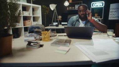 Yakın plan Afro-Amerikan iş adamı hipster ofisinde telefonla konuşuyor..