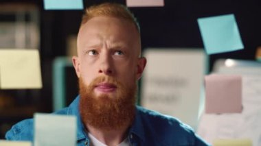 Odaklanmış hipster adam modern işyerindeki çalışma masasına etiket yapıştırıyor..
