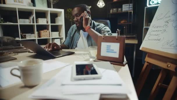 Překvapený africký podnikatel mluví mobilní telefon v hipsterské kanceláři. — Stock video