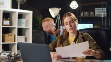 Sinirli iş kadını karanlık ofiste video görüşmesi sırasında belgeler hakkında tartışıyor..