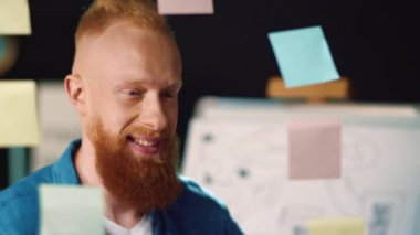 Çıkartma tahtasında fikirleri seçen neşeli iş adamı. Çıkartmalarla çalışan adam.