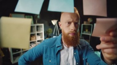 Ofisteki fikir panosuna kırmızı kafalı hippi etiketi yapıştırıyor. Notları okuyan adam