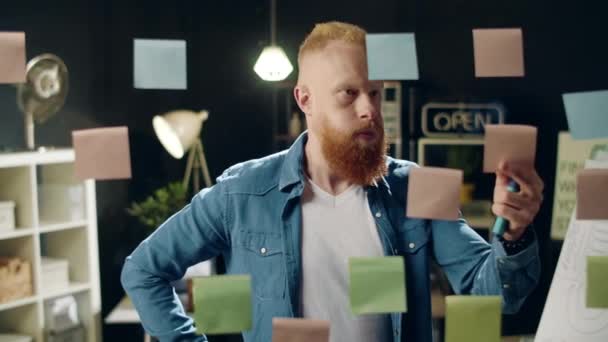 Closeup unavený podnikatel sundávat samolepku ze skleněné desky v hipster kanceláři — Stock video