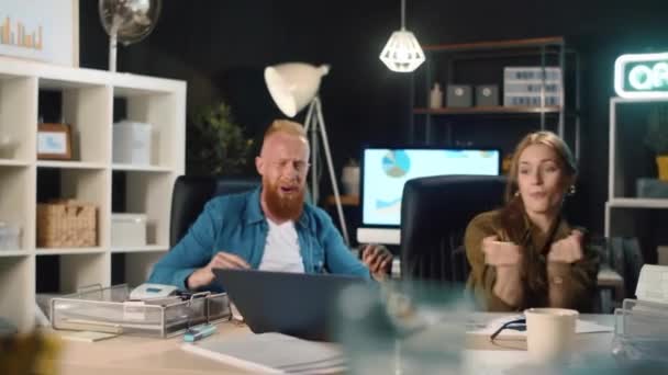 Feliz joven hombre y mujer celebrando la victoria con el ordenador portátil en la oficina. — Vídeos de Stock