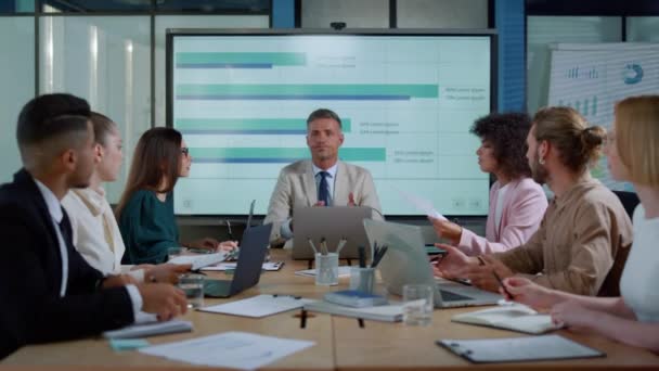 Руководитель мужского пола беседует с коллегами о финансовом успехе в офисе — стоковое видео