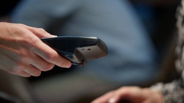 Kapalı iş kadını elleri pos terminali üzerinden cep telefonuyla ödeme yapıyor.
