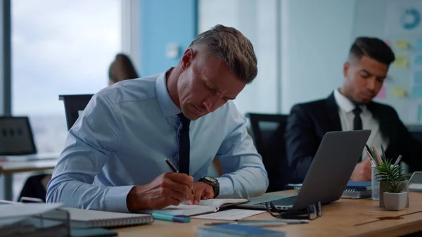 Homem de negócios focado fazendo anotações no caderno. Empreendedor masculino digitando no laptop — Fotografia de Stock
