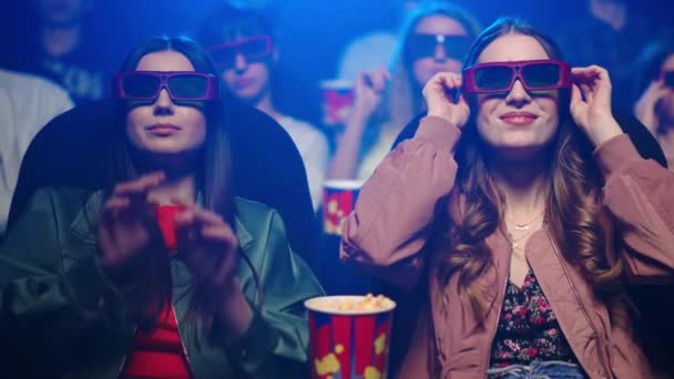 Smiling women putting 3d glasses in movie theater. Happy girls enjoying film. — Stock Video