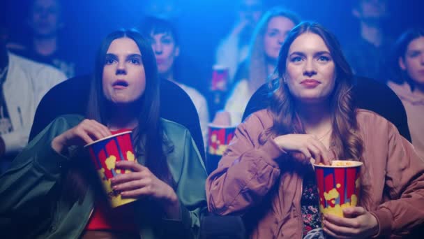 Hermosas mujeres disfrutando del cine. Chicas guapas comiendo en el cine. — Vídeo de stock