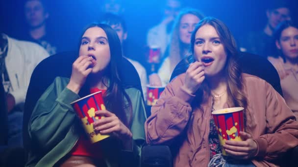 Sinema salonunda patlamış mısır yiyen mutlu kadınlar. Neşeli kızlar film izliyor.. — Stok video