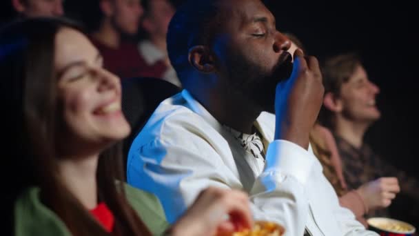 Amigos alegres riendo en el cine. Hombre alegre comiendo palomitas de maíz en interiores. — Vídeos de Stock