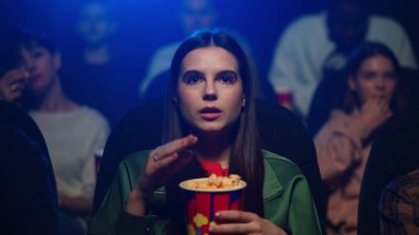 Genç bir kadın sinemada ilginç bir film izliyor. Patlamış mısır yiyen çekici kız.