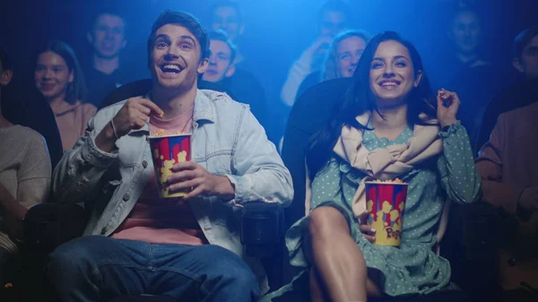 Cheerful couple watching movie indoor. Happy friends having fun in cinema.