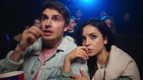 Mladý pár se bojí v kině. Mladý muž házet popcorn dovnitř. — Stock video