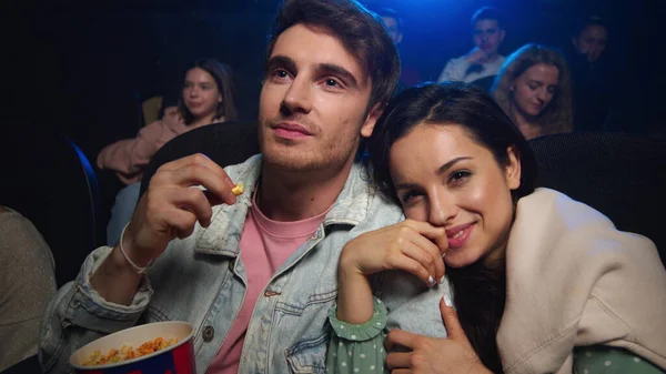 Cheerful couple having fun in cinema. Man and woman watching film indoor.