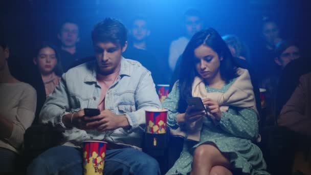 Sinema salonunda hayal kırıklığına uğramış kadın ve erkek cep telefonu ekranına bakıyor.. — Stok video