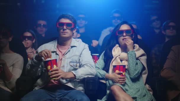 Una coppia attraente che mangia popcorn al cinema. Amici che guardano film in occhiali — Video Stock