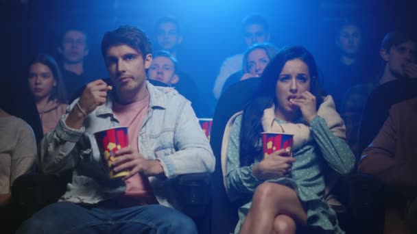 Сумна пара їсть попкорн у кіно. Занепокоєна жінка витирає сльози в приміщенні . — стокове відео