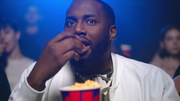 非洲男人在电影院吃爆米花.看电影的非裔美国人. — 图库视频影像