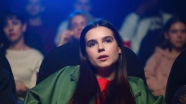 Sinemada korku filmi izleyen korkmuş bir kadın. Kız merak ediyor