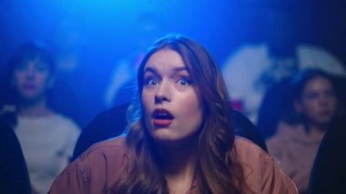 Genç bir kadın kötü filme kızıyor. Sinema salonundaki üzgün kız akıllı telefona benziyor.