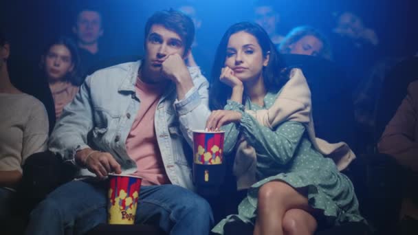 Verärgertes Paar isst Popcorn im Kino. Frustrierte Menschen schauen Film in Halle. — Stockvideo