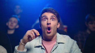 Sinemada korku filmi izleyen şok olmuş bir adam. Filmde patlamış mısır yiyen korkmuş adam.