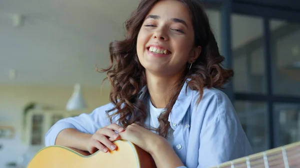 Kvinna med gitarr skrattar åt kameran hemma. Flicka med akustisk gitarr — Stockfoto